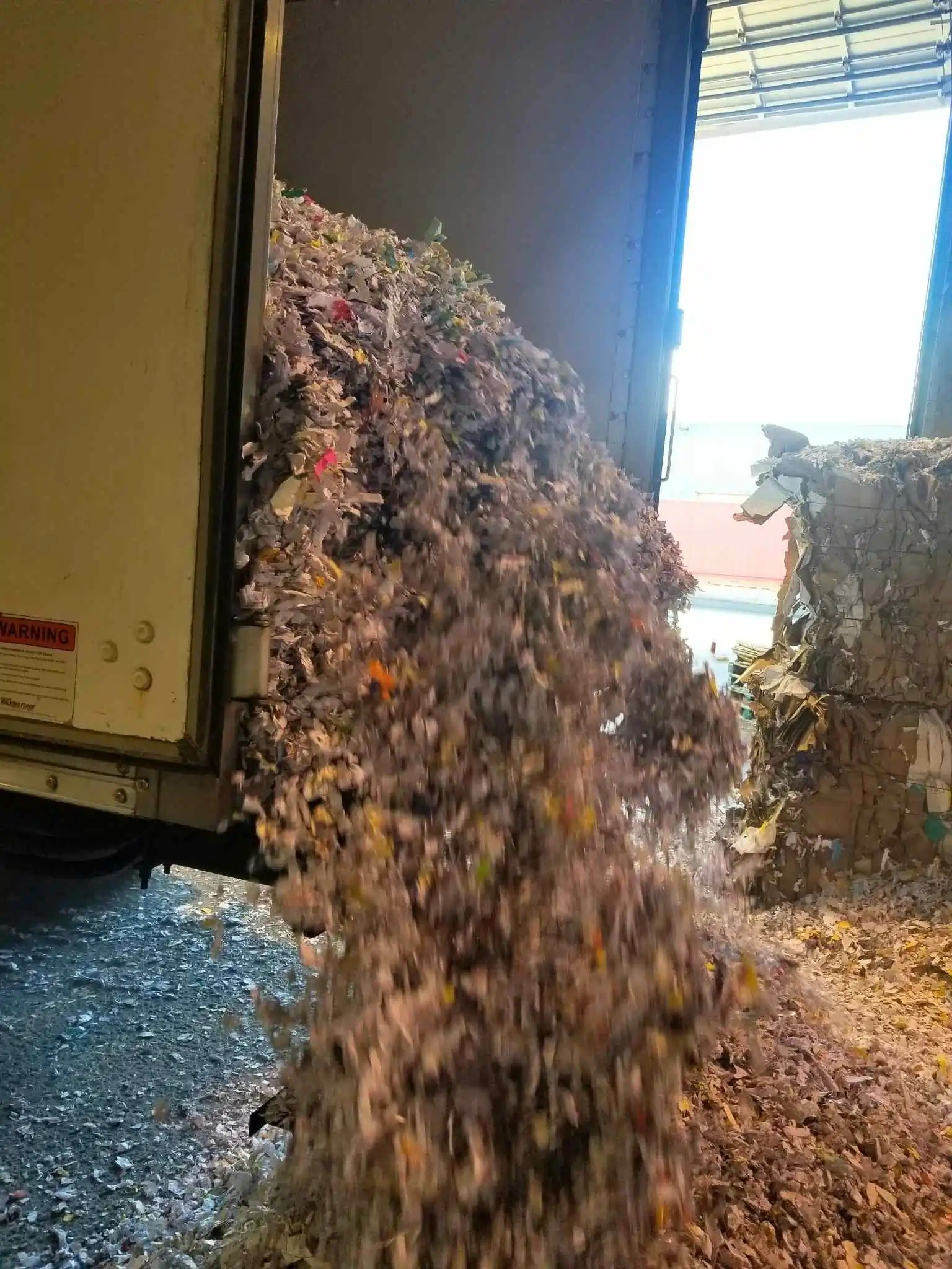 an infoshred truck dumping out shredding paper at a recycling depot